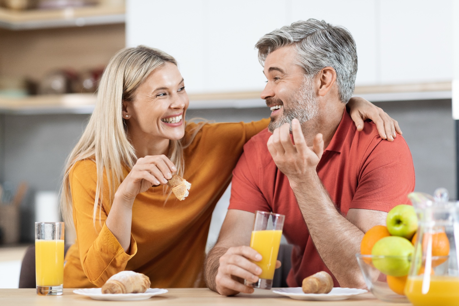 Cheerful man and woman having snack and talking at home